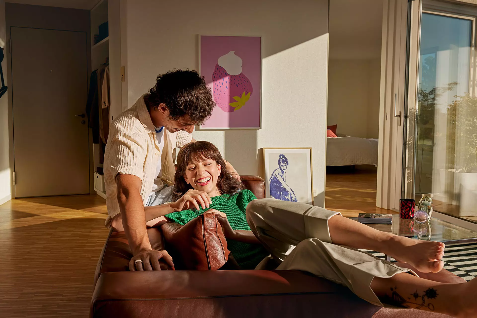 Ein Pärchen lsitzt und lacht auff dem Sofa in Ihrer Wohnung